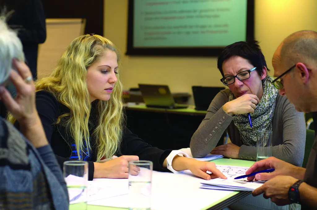 Consultant and small-business owner reviewing responsible business practices together with other people in the team.