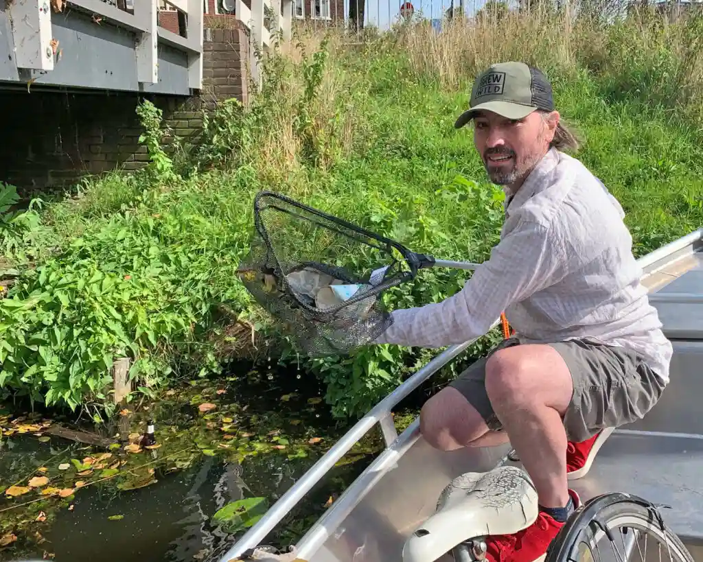 Peter fishing for plastics in Haarlem, North Holland, aboard the De Pinguïn boat.