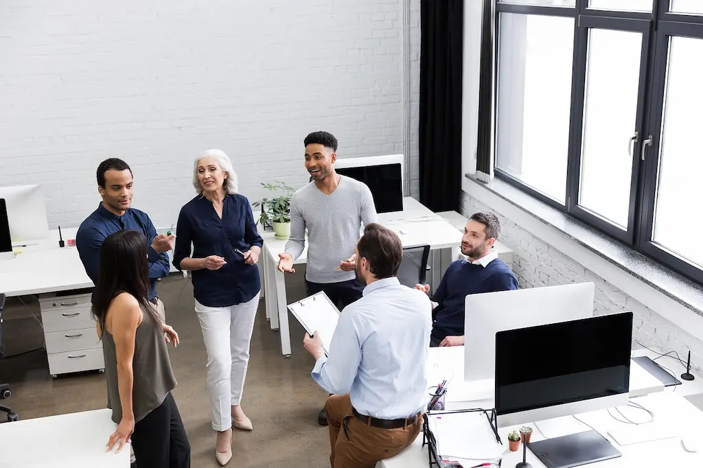 Diverse office team discussing business priorities and shared responsibilities for stronger social and environmental performance.