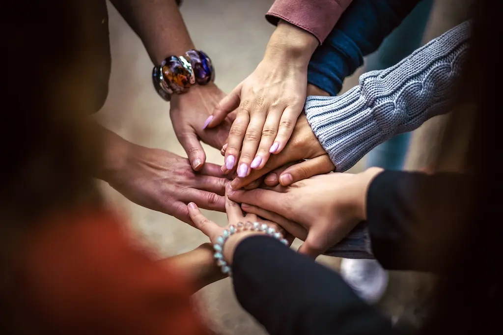 People stacking hands together to represent Sustainable Development Goals collaboration