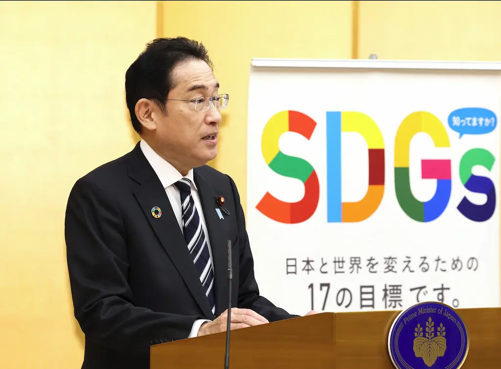 Prime Minister Kishida speaking at the Japan SDGs Award beside a Sustainable Development Goals display